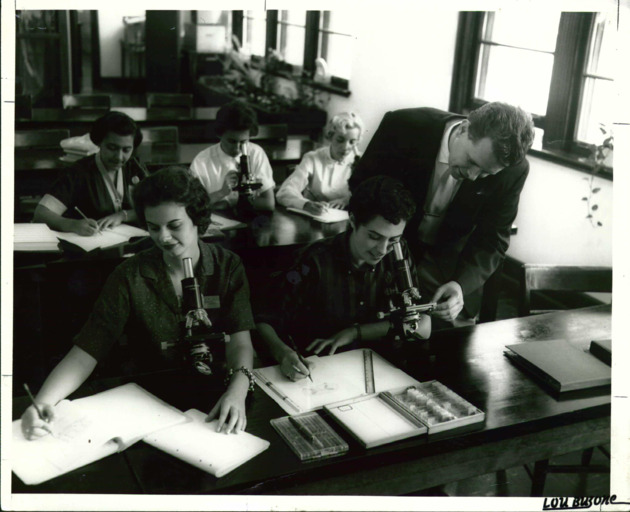 A professor checks the work a student during Biology class