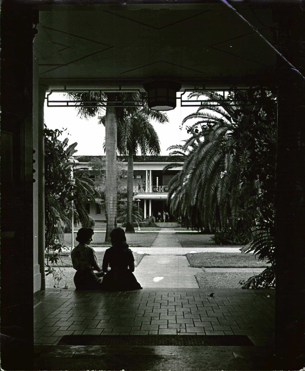 Two students talking on the steps of Kelley House with Adrian Hall in the background