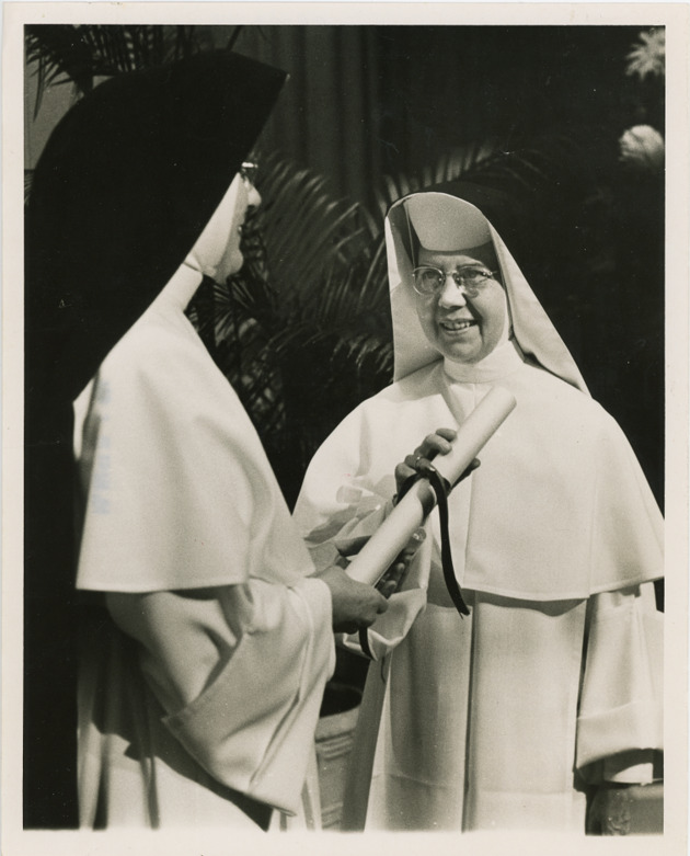 Mother Genevieve Weber, O.P., hands Sister Mary Dorothy Browne a scroll at her inauguration as President