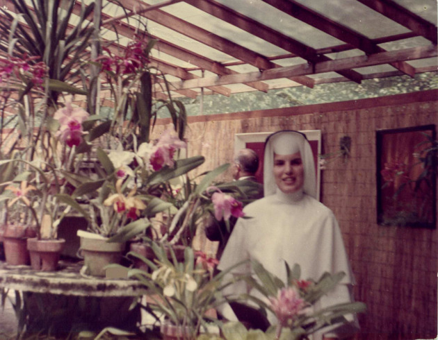 Sister Linda Bevilacqua, O.P., in Dominican habit poses in a greenhouse