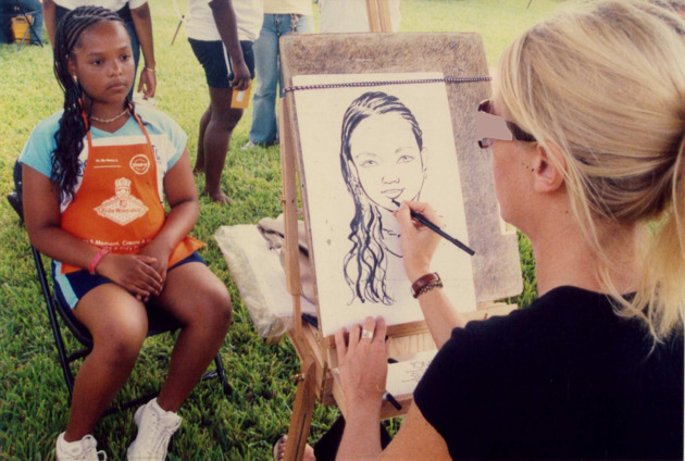 A sketch artist draws a portrait of a young girl during Alumni and Family Weekend